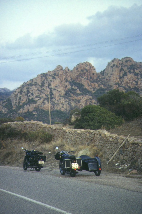 Ein Solo–Motorrad und ein Victoria–Gespann am Straßenrand.